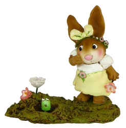Girl rabbit in a spring dress looking at a worm poking its head out