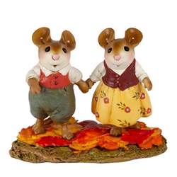 Young couple mice, hold hands walking through the fall leaves.