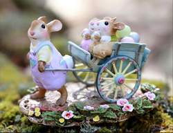 Easter Bunny gives a ride to two young bunnies in a decorated hand cart full of Easter Eggs.