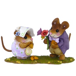 Male mouse in tails brings flowers to female mouse