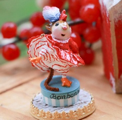 A lovely mouse does the can-can atop a box of bon-bons representing a French hen 